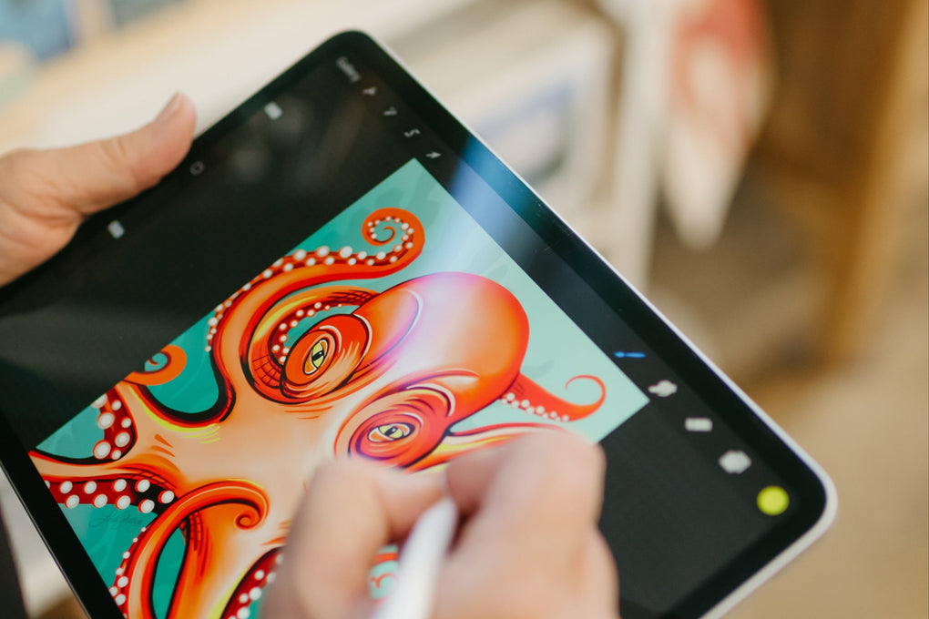 Person using a stylus to draw on a digital tablet with a colorful octopus design.